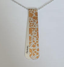 Load image into Gallery viewer, The Angelica layered necklace has golden copper tones pattern reminiscent of a cathedral frieze.  The off centre bend allows for the affirmation word "Serenity" to be exposed.  This is the perfect layering necklace with a 30" stainless steel, hypo-allergenic, tarnish free chain and a recycled aluminum pendant.  The pendant measures 3 1/4" long x 3/4" wide. The aluminum makes it light weight for easy wear.