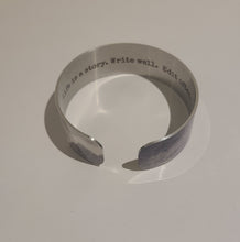 Load image into Gallery viewer, We have picked some of our favourite pieces and paired them with an inspirational saying that resonates with us. Quote inside: "Life is a story. Write well. Edit often." Made of aluminum each cuff is hypo-allergenic, lead and nickel free, with no toxic finishes. Everything is printed with a permanent dye which gives a nice vibrant finish. Cuffs are super light weight and adjustable allowing them to be molded to fit most sizes. Each cuff is 3/4" thick