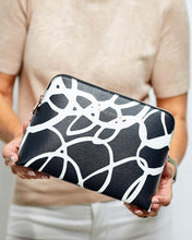 Load image into Gallery viewer, The Bardot Swirl Case is a funky, black and white art print case with a firm structure so it stands tall in your bathroom.  Perfect as a make-up or toiletry case for those weekend getaways.  It's Rose Gold zippr is a beautiful additional detail.  Pair it with the Emma Hanging Toiletry case for an Exclusive Bundle!  Internal Features:  2 Flat Pockets Lining: Polyester Sateen Twill Secure Zip Material: Vegan Leather  Hardware: Rose Gold  Dimensions: H18.5 x W26 x D9 cm. Shown: Person holding Bardot Case