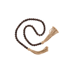 Load image into Gallery viewer, A simple must have coffee table styling piece, these wooden beads add a touch of feel-good style to your living space. Inspired by Mala beads used for prayer and meditation, they encourage mindfulness, peace, and clarity. Dimensions: 48"L x 0.5"W x 0.5"H  Materials: Paulownia Wood, Jute rope tassels - Carved from paulownia wood and finished with a brown wash