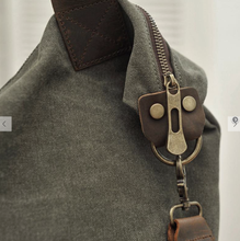 Load image into Gallery viewer, This ultra-spacious Canvas Tote Handbag can effortlessly carry everything you need when you're headed out for the day. With double top leather handles and an adjustable strap, you'll get a comfortable carrying position whether you go hands free or not. It also features an exterior front pocket and interior zippered compartments to stash your essentials, all within a zippered closure for security and easy access. Size: 20" X 17" Materials: Canvas, Leather. Shown: Zipper detail of Tote