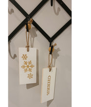 Load image into Gallery viewer, These fun and whymsical Christmas Hangers will create the perfect welcome this holiday season. With a Christmas Message on one side, and a Winter Symbol on the other, this white and gold decor will look beautiful in any room. Put it anywhere...doorknobs, walls, mantles...and you can even use it as ornaments on your tree. 2 Styles to choose from: Cheer Noel. Size: 7.5 x 3.5 x .25". Shown: Cheer/Snowflakes