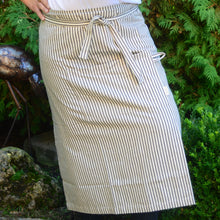 Load image into Gallery viewer, Look professional in this stylish and classic Ticking Stripe patterned, 100% cotton apron! Comes complete with a utility front pocket. Machine wash gentle cycle. Measures: 34" w x 34" l Shown: Person wearing Ticking Stripe Apron