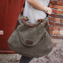 Load image into Gallery viewer, This ultra-spacious Canvas Tote Handbag can effortlessly carry everything you need when you're headed out for the day. With double top leather handles and an adjustable strap, you'll get a comfortable carrying position whether you go hands free or not. It also features an exterior front pocket and interior zippered compartments to stash your essentials, all within a zippered closure for security and easy access. Size: 20" X 17" Materials: Canvas, Leather. Shown: Person carrying Grey Tote