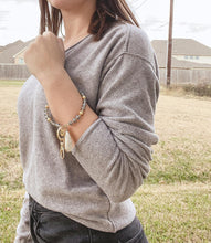 Load image into Gallery viewer, This Beaded Bracelet Keychain features a glimmering druzy white stone that will truly enchant those around you with its unique texture. The keychain has a 18k gold ion-plated stainless steel teardrop setting. It is surrounded with gold metal and grey glass beads for an elegant look. Exclusively from Kinsley Armelle. Details: Materials: 18K Yellow Gold Ion Plated Stainless Steel, druzy stone, glass and metal beads Size: 3" d Key Ring. Shown: person wearing keychain