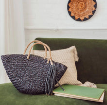 Load image into Gallery viewer, Classic black handbag with its thick handle and high-quality structure. It features a removable tassel made of thick jute rope and wooden beads. Use the tassel as a home accent, a doorknob hanger, a wall hanging, or over another bag. Hand-woven by independent Balinese artisans in a fair-trade environment, each bag is crafted using sustainably-harvested mendong grass. Size: 20" L x 6.5" W x 16" H Material: Handbag: Mendong grass; Tassle: Jute rope and wooden beads