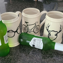 Load image into Gallery viewer, Add to your drinkware collection with these unique beige ceramic beer steins.  Perfect for entertaining on the patio or cottage deck, or chilling in front of the tv.  Pair them with your favourite bottle for a great Father's Day, Birthday or Just Because gift.  3 styles to choose from:  Antlers Sunglasses Bicycle Capacity:  18oz  Material:  Ceramic