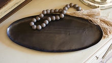 Load image into Gallery viewer, This gorgeous oval tray is our most versatile and sustainable piece yet.  Each one is uniquely designed with recycled iron, giving it a unique finish.  Perfect for any room to enhance your decor. Perfect for entryways, mantels, countertops, kitchen tabletops or coffee tables.  Makes a great hostess or house warming gift.  Add any of our candles, diffusers or beads for a completely sophisticated look.   Size:  19.75" L x 8.25" W  Material:  Recycled Iron  **Hand wipe with damp cloth