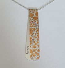 Load image into Gallery viewer, The Angelica layered necklace has golden copper tones pattern reminiscent of a cathedral frieze.  The off centre bend allows for the affirmation word &quot;Serenity&quot; to be exposed.  This is the perfect layering necklace with a 30&quot; stainless steel, hypo-allergenic, tarnish free chain and a recycled aluminum pendant.  The pendant measures 3 1/4&quot; long x 3/4&quot; wide. The aluminum makes it light weight for easy wear.
