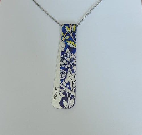 The Eloise layered necklace has blue and silver tones and floral pattern.  The off centre bend allows for the affirmation word 