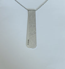 Load image into Gallery viewer, The Etched Fostoria layered necklace has silver on silver tones with floral pattern.  The off centre bend allows for the affirmation word &quot;Believe&quot; to be exposed.  This is the perfect layering necklace with a 30&quot; stainless steel, hypo-allergenic, tarnish free chain and a recycled aluminum pendant.  The pendant measures 3 1/4&quot; long x 3/4&quot; wide. The aluminum makes it light weight for easy wear.

