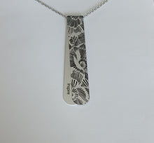 Load image into Gallery viewer, The Midnight Bouquet layered necklace has Silver and Black tones with etched floral pattern reminiscent of a penciled sketch.  The off centre bend allows for the affirmation word &quot;Inspire&quot; to be exposed.  This is the perfect layering necklace with a 30&quot; stainless steel, hypo-allergenic, tarnish free chain and a recycled aluminum pendant.  The pendant measures 3 1/4&quot; long x 3/4&quot; wide. The aluminum makes it light weight for easy wear.

