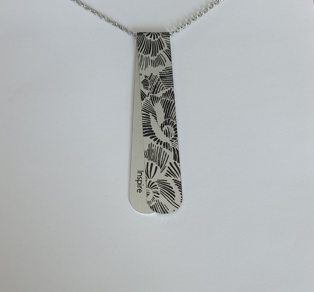 The Midnight Bouquet layered necklace has Silver and Black tones with etched floral pattern reminiscent of a penciled sketch.  The off centre bend allows for the affirmation word 