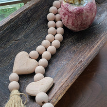 Load image into Gallery viewer, This beaded pink heart garland makes an easy and textural addition to your home décor. Blessing Beads are a lovely way to add a little sentiment to your space and a fun touch to your favorite piece. Drape it over your chair, have it spilling onto your coffee table or hang them from an armoire. They are used to bring good wishes, healing and luck. · Dimensions: 1.96&quot;L x 0.59&quot;W x 33.4&quot;H Materials: Paulownia Wood, Jute Carved from paulownia wood and finished with a light pink wash
