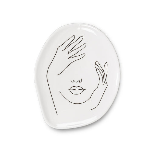 Add an artistic touch to your keepsakes, coins and more with this Face Trinket Plate. Crafted out of porcelain, the subtle Expressionistic lines of a woman’s visage also gives this unique plate its shape.  A stylishly unexpected way to store your jewelry or simply keep keys and other knick-knacks close at hand when needed.  Will definitely make a statement to any decor.  These plates can be used as tea or dessert dishes. Size:  Approximately 5 x 4