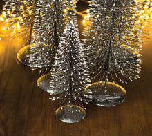 Load image into Gallery viewer, Create a winter wonderland on your mantel, sideboard or dining room table with these charming bottle brush Christmas trees in on-trend hues. Crafted from sisal fiber sprayed with festive glitter and perched on metal stands. Colour: Dark Grey. 5 Sizes Available: Extra Large: 24&quot;H Large: 20&quot;H Medium: 16&quot;H Small: 12&quot;H Extra Small: 8&quot;H
