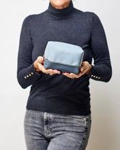 Load image into Gallery viewer, The Baby Tara cosmetic case is a beautiful top zipper makeup bag perfect for travel or storage. Gorgeous chambray two-tone colours and a soft texture, this travel case is spacious enough to fit your makeup or toiletries for a weekend away! Features: Lining: Polyester Sateen Twill Closure: Secure Zip Material: Vegan Leather Hardware: Light Gold Dimensions: W18 x H11 x D9.5cm. Shown: Person holding Tara cosmetic case
