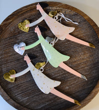Load image into Gallery viewer, We just love these beautiful and whimsical angel ornaments.  Hand Painted and perfectly adorned with metallic wings, hearts and shoes, these ornaments will compliment any tree and christmas decor.  Add them to your gifts for an added special touch.  Size:  8&quot; L  Material:  Polyresin. 3 colours to choose from: Green, Pink, White

