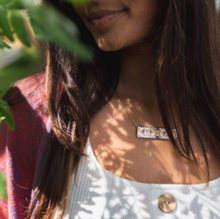 Load image into Gallery viewer, This beautiful SILVER and Black Astec Floral set includes:  (1) Bar Necklace (can be worn either way) - Quote on back : &quot;make history&quot; (1) Bookmark - Quote: &quot;Well behaved women seldom make history - Eleanor Roosevelt&quot; 18&quot; adjustable silver chain.  Crafted from upcycled trophy aluminum.  Each piece is eco-friendly, hypo-allergenic, lead and nickel free. Shown: Person wearing necklace.
