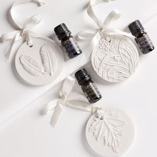 Load image into Gallery viewer, These Ceramic Diffuser &amp; Essential Oil Gift Sets provide a portable touch of beauty; wherever, whenever. The ceramic diffuser porous stone features an elegant nature inspired design and quickly absorbs, retains and gently emits a concentrated blend of diffusing oil. Gift Boxed.  3 Scents to choose from:  Lavender Fields Sandalwood Jasmine Lyrical Angelica Perfect to hang in your car, closets, powder rooms or any small spaces around your home.
