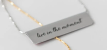 Load image into Gallery viewer, This beautiful SILVER and FUSHIA PINK FLORAL set includes:  (1) Bar Necklace (can be worn either way) - Quote on back : &quot;live in the moment&quot; (1) Bookmark - Quote: &quot;Live in the moment &amp; see the beauty of all before you.  The future will take care of itself.&quot; 18&quot; adjustable silver chain.  Crafted from upcycled trophy aluminum.  Each piece is eco-friendly, hypo-allergenic, lead and nickel free. Shown: Back of necklace with quote.
