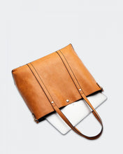 Load image into Gallery viewer, The Nutmeg Nevada Bag is a great tote style which can double as a laptop or work bag. Featuring a luxurious suedette lining, this shoulder bag is spacious and functional with enough room to carry all your essentials and more! Features: 2 Slip Pockets 1 Zip Pocket Feet on Base Internal Lining: Suedette Strap: Height 25cm Extension Strap: Detachable Webbing 41cm Magnetic Clasp Material: Vegan Leather Hardware: Light Gold Dimensions: H31 x W41 x D11 cm. Shown: laptop fitting into bag
