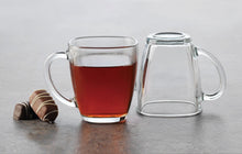 Load image into Gallery viewer, Enjoy the contemporary style, and seeing what&#39;s inside, when you sip from this square clear glass mug.  Serve up hot toddies, cappuccinos, lattes, tea, hot cocoa, and more. Constructed from high-quality glass for everyday durability.  Pair it with our beautiful teas and accessories for the ultimate tea set gift-box.  Size:  4&quot; L  Material:  Clear Glass  Capacity:  14oz
